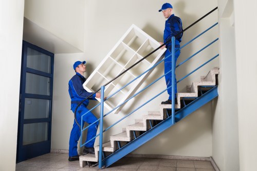 Removalists handling furniture in a typical North London flat staircase