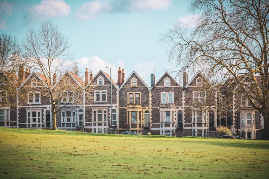A quiet residential street in Finsbury Park showing row of Victorian-style terraced houses with bay windows, brickwork, and chimneys, under a cloudy sky. The pavement runs alongside the houses with me